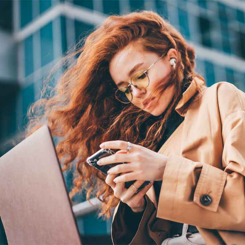 Woman on computer and cell phone at the same time while working on an online business